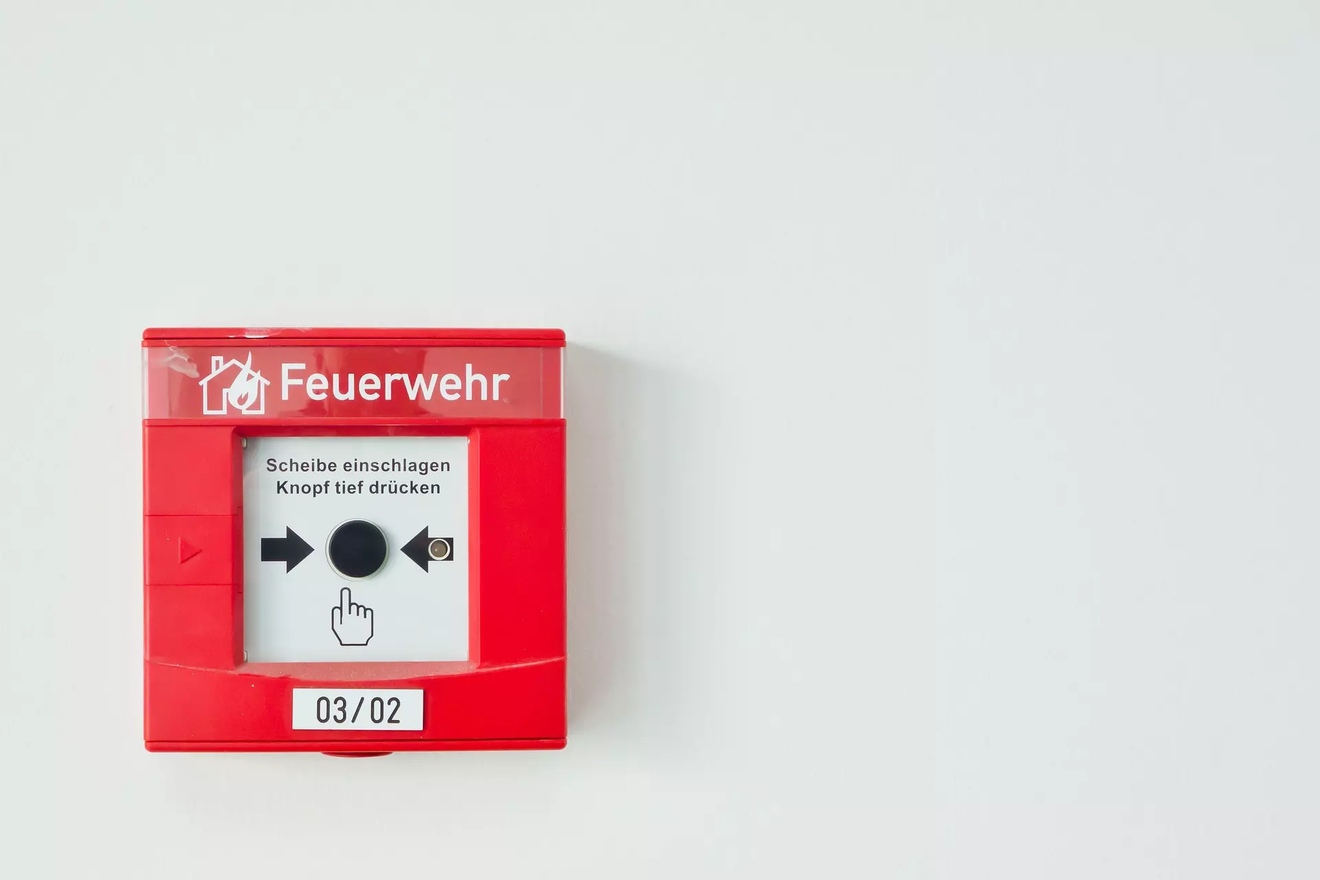 Bild zeigt einen roten Druckknopfmelder mit der Aufschrift "Feuerwehr"